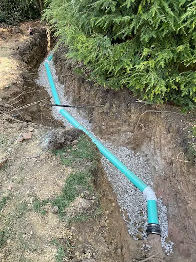 Titan Plumbing & Drains installing a new pipe in an outdoor trench for improved drainage.