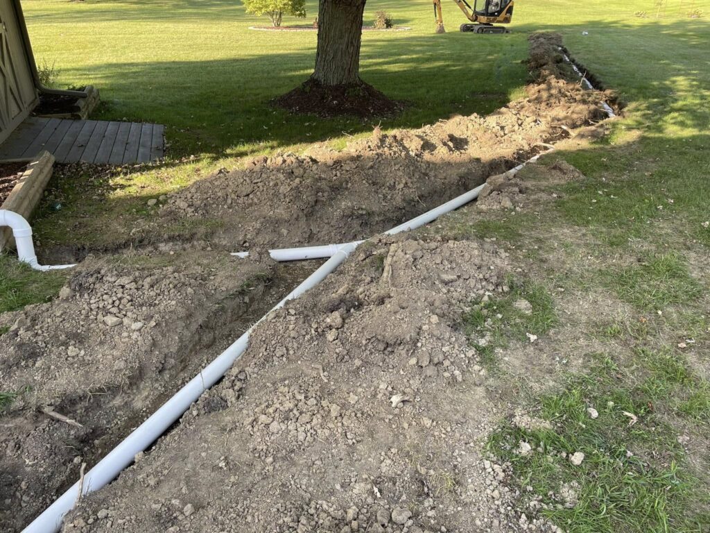 A Titan Plumbing & Drains technician is installing drainage pipes in a yard to improve water flow.