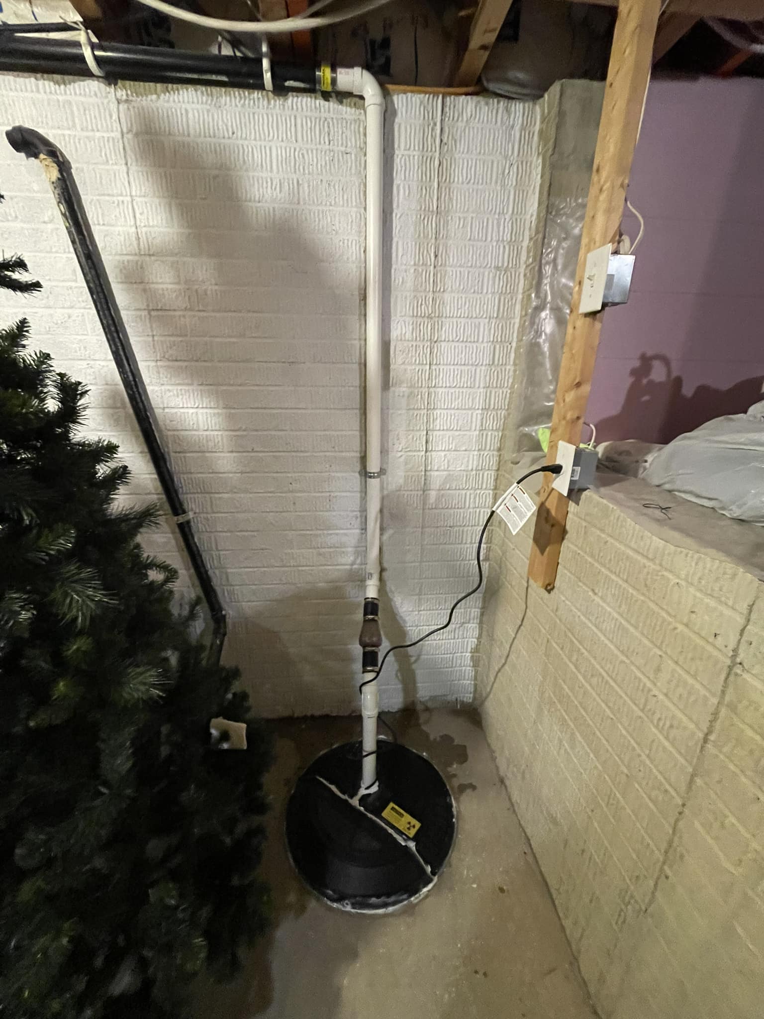 A sump pump setup in a basement shows Titan Plumbing & Drains plumbing repair work.