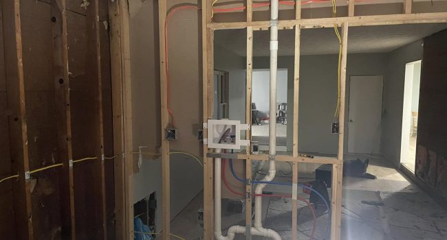 Home renovation in progress by Titan Plumbing & Drains, showing exposed pipes and wiring with construction debris.